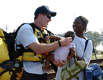 A member of FEMA's Urban Search and Rescue task force assists a mother and child stranded by flood waters after Hurricane Katrina. (Jocelyn Augustino, FEMA, August 30, 2005, National Archives)